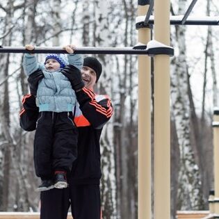 Child being helped on the jungle gym by parent